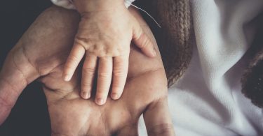 Рука ребенка на руке взрослого человека